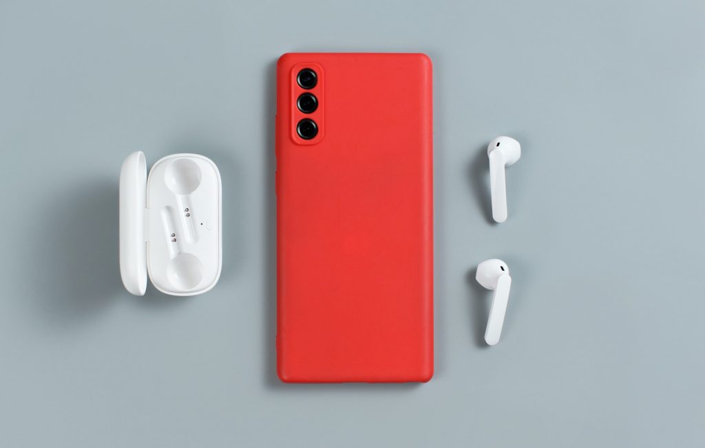 Smartphone with red cover and white wireless earphones